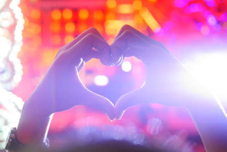 Heart Shaped Hand against Bokeh Red Background bright lightsの写真素材