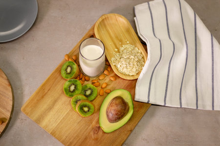 Half an avocado, slices of kiwi, almond, oats and milk on a board covered with a kitchen towel. Ingredients for a nutritious and healthy tasty breakfast.の写真素材
