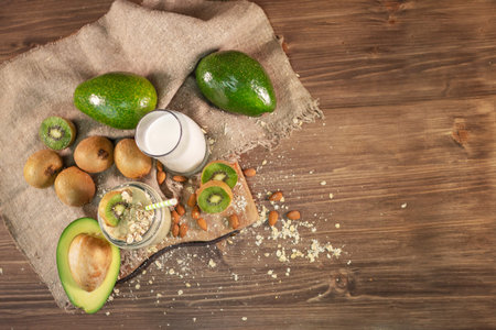 Fresh smoothie made of kiwi, avocado, oatmeal and skim milk near a burlap towel. Decorated on top. Morning meal in the village with fresh ingredients. Top view.の写真素材