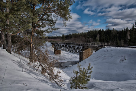 Railway bridge over the river in the winter forestの写真素材