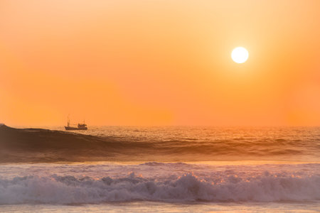 Small ship sailing at colorful sunset in Sri Lankaの写真素材