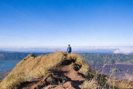 Girl tourist with a backpack walking on top of the Gunung Batur volcanoの写真素材