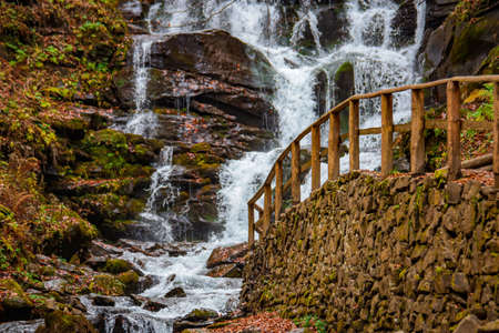 waterfall in the autumn forest with authentic wooden handrails. wallpaper, screensaver, posterの写真素材