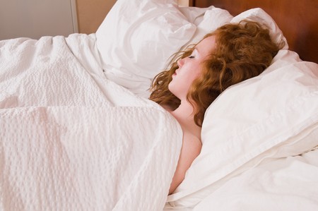 Pretty pale redhead lying in bed asleepの写真素材