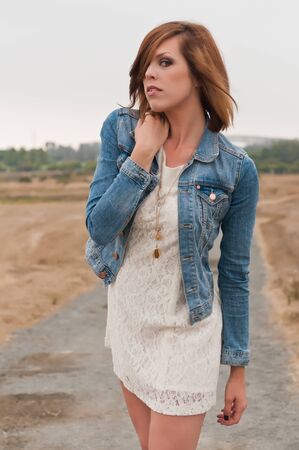Tall pretty brunette in a white dress and denim jacketの写真素材