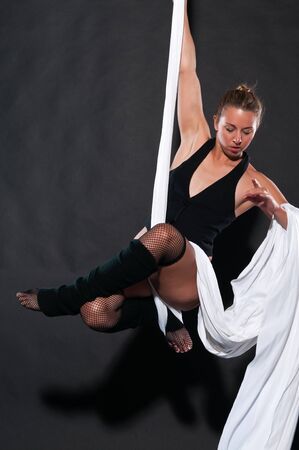 Athletic blonde aerialist suspended from white fabricの写真素材