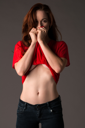 Pretty pale redhead in a red blouse and jeansの写真素材