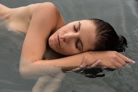 Pretty nude redhead in a pool of waterの写真素材