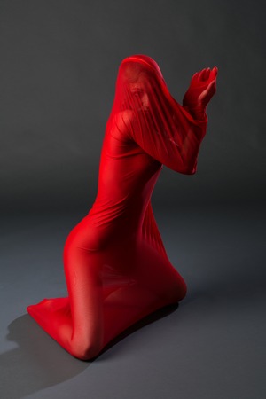 Slender young woman in a sheer red body stockingの写真素材