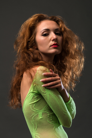 Slender young redheaded woman in a green fishnet body stockingの写真素材