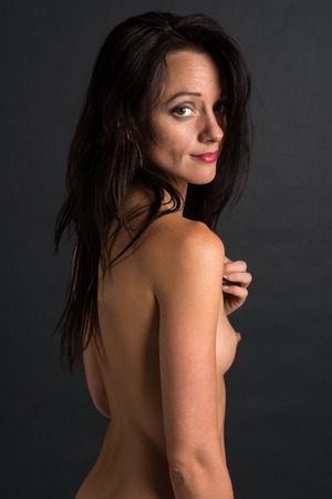 Pretty slender brunette standing nude on grayの写真素材