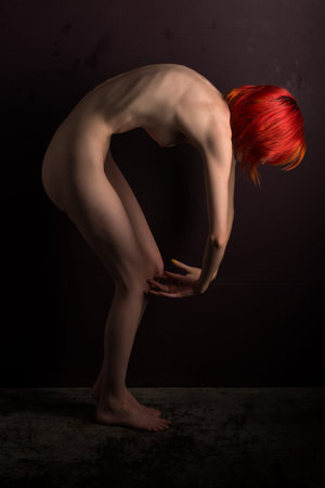 Pretty slim pale nude woman with dyed red hairの写真素材