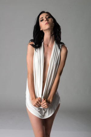 Pretty young slender brunette in a white sheath dressの写真素材