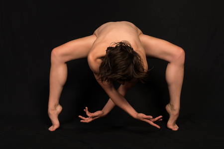 Slender young brunette standing nude on blackの写真素材