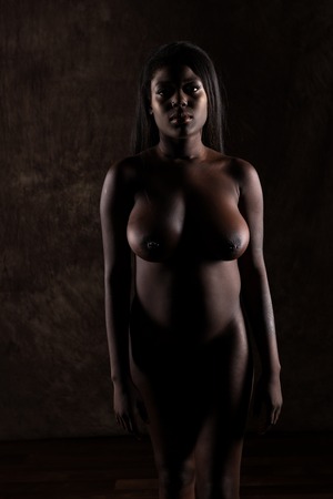 Shapely Ghanaian woman standing nude in deep shadowの写真素材