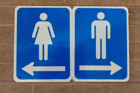 Men's and women's restroom signs bolted to a brick wallの写真素材