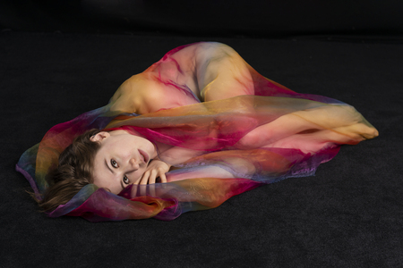 Petite athletic brunette wrapped in sheer rainbow tulleの写真素材