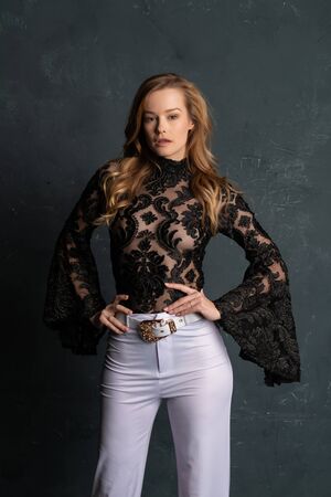 Beautiful tall blonde woman in a black lace blouse and white slacksの写真素材