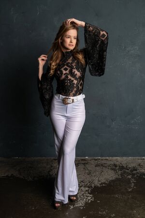 Beautiful tall blonde woman in a black lace blouse and white slacksの写真素材