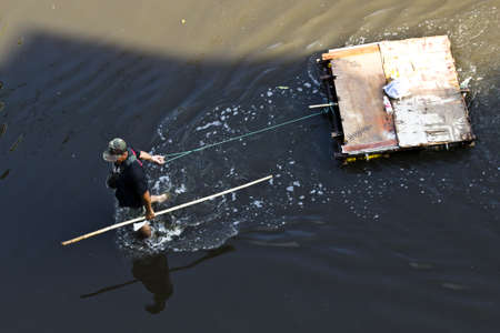 Bangkok - November 2011: The villagers pulling the hand-made rafts to go to flooding service center for recieve the foods in big flood on 7 November 2011at Ramintra Soi 14 road, Ladprao, Bangkok, Thailand.のeditorial素材