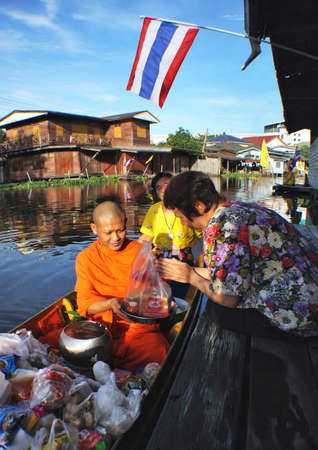 Buddhist monks recieve food from thai womanのeditorial素材