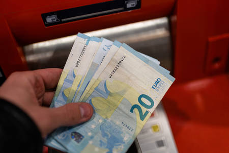 Man hand holding euro banknotes at ATM machine in the bank in Shopping centreの写真素材
