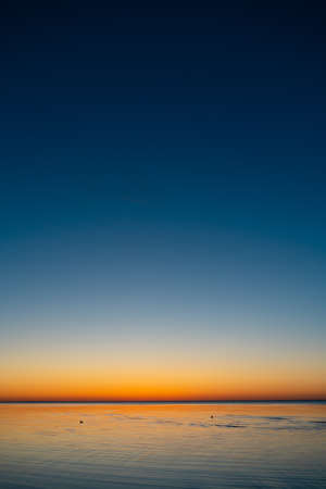 Vivid amazing sunset in Baltic States - Dusk in the sea with horizon illuminates by the sunの写真素材