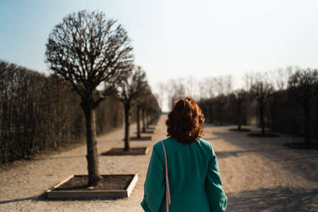 Young fashion lover woman waling in a park wearing vivid green jacket and a colorful skirtの写真素材