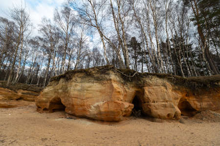 Limestone beach at the Baltic Sea with beautiful sand pattern and vivid red and orange color - Tourist writings on the walls and rocks and sand - Veczemju Klintis, Latvia - April 13, 2019の写真素材