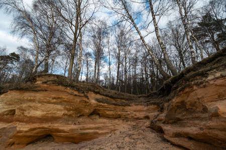 Limestone beach at the Baltic Sea with beautiful sand pattern and vivid red and orange color - Tourist writings on the walls and rocks and sand - Veczemju Klintis, Latvia - April 13, 2019の写真素材