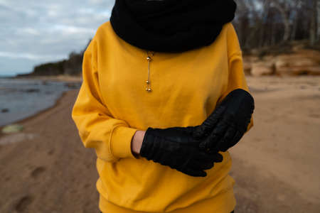 Happy sport and fashion lover enthusiast working out on a beach wearing bright yellow sweater and black gloves and a cap in Spring - Limestone in the backgroundの写真素材
