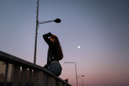 Young woman enjoying sunset with a view over Moon and clear blue skyの写真素材
