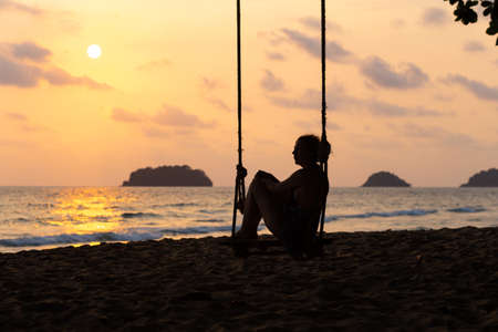 Travel blog photo: Silhouette of a woman in a dress during sunset with a view over sea with a small isand on the horizonの写真素材