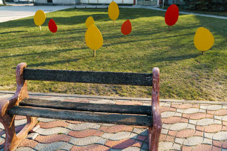 Small city bench standing on a pavement near a treeの写真素材