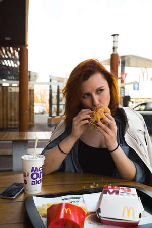 MARUPE, LATVIA - APRIL 22, 2019: Young woman drinking McDonalds coffee outdoors in a field during sunsetのeditorial素材
