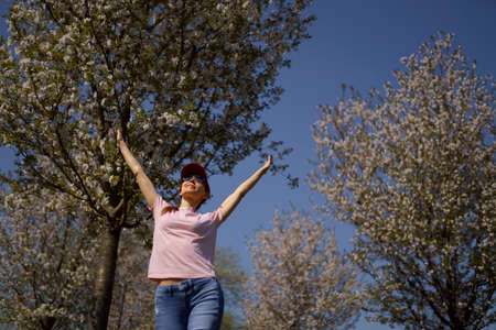 Successful business woman enjoys her leisure free time in a park with blossoming sakura cherry trees...