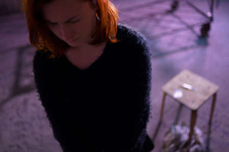 Face portrait close up of drug addiction redhead caucasian white young woman wearing black sweater,...