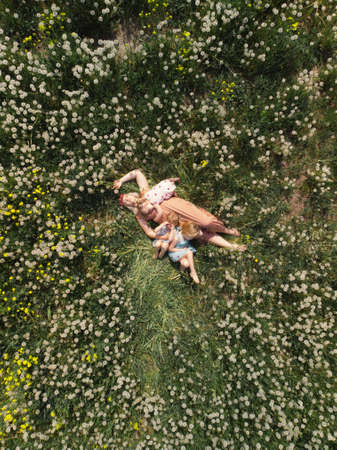 Aerial drone: Mother having quality funny playing time with her baby girls at a park blowing...