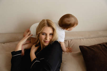 Young blonde mother having quality time with her baby boy son at family home flat - Wearing black...