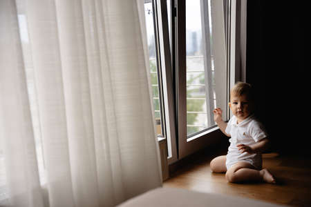 Young blonde mother having quality time with her baby boy son at family home flat - Wearing black budoir dress costume sleeping gownの写真素材