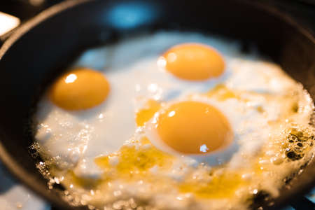 Egg omelette is being prepaired in a frying pan close up - Three yellow eggs in Eastern Europe Latvia Riga.の写真素材