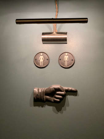 WC sign on the grey wall with a hand pointing right and a lamp illuminating in Eastern Europe Latvia...