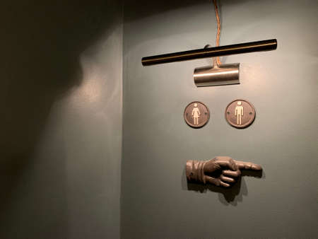 WC sign on the grey wall with a hand pointing right and a lamp illuminating in Eastern Europe Latvia Riga bar cafe restaurantの写真素材