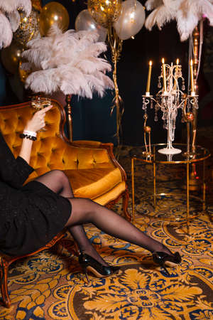 Woman in black with champagne glass at Crazy luxury corporate event decoration with feather and gold in Eastern Europe Latvia Riga bar cafe restaurantの写真素材