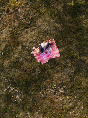 Aerial: Young mother with her baby girl daughters on a picnic in a park - Family values warm color summer scene drone top shot from aboveの写真素材