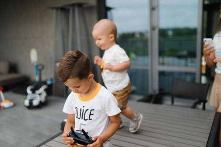 Young mother playing and having fun with her baby boy son brothers in a green garden with cars - Family values warm color summer scene - Eastern European Latvia Rigaの写真素材