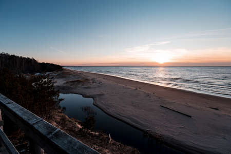 Sunset at Saulkrasti white dune. View from wooden walkpath over sea, small river and sky.