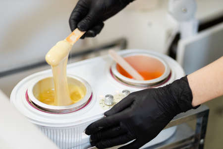 Female master of hair removal prepares wax for depilationの写真素材