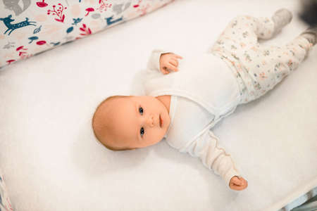 Toddler lies in crib looking up at homeの写真素材