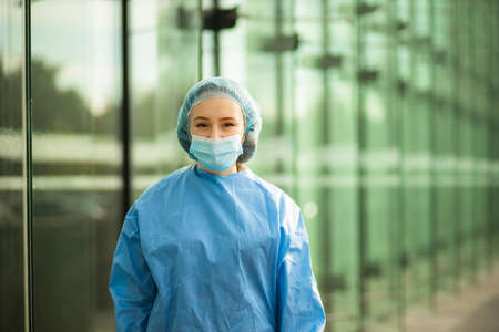 Health care medical female doctor or nurse in surgical mask and surgical cap looking at youの写真素材